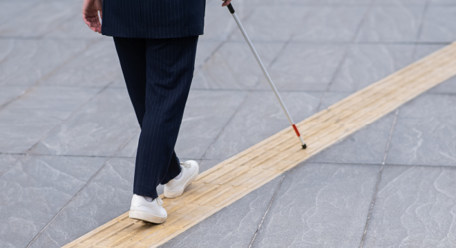 写真：白杖を使って点字ブロックの上を歩いている人